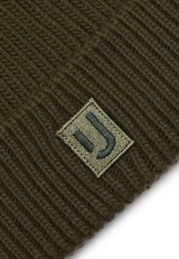 Bonet de tricotat, de culoare verde măsline, cu textură în relief și o etichetă de țesătură rectangulată care prezintă un logo în relief, de culoare verde închis.