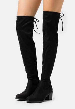 Bottes noires montantes en daim souple, dotées d'un talon bloc et d'une fermeture éclair latérale, avec des lacets en haut pour un ajustement.