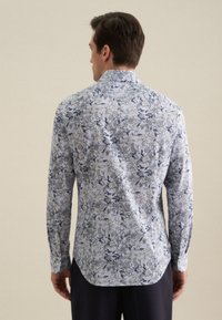 Lange mouwen blouse in lichtblauw met bloempatroon in navy en crème. Heeft knoopmanchetten en een puntige kraag. Ontworpen voor een getailleerde pasvorm.