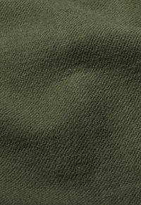 Olijfgroen stof met een getextureerd, geweven patroon. Het oppervlak lijkt zacht en enigszins fuzzy, met diagonale lijnen over het materiaal.