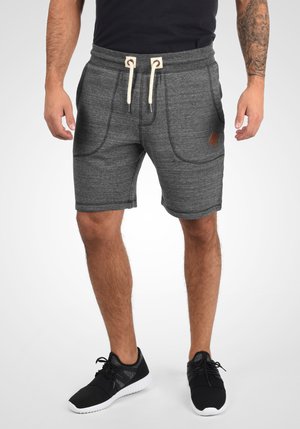 Shorts de sport gris avec une taille élastique à cordon de serrage, dotés de deux poches latérales et d'un petit patch en cuir marron sur le devant.