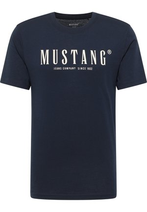 Tumesinine puuvillane T-särk lühikeste varrukatega, mille esiküljel on valge print "MUSTANG JEANS COMPANY SINCE 1932".