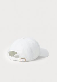 White baseball cap made of cotton, featuring a relaxed fit, curved brim, and an adjustable strap with metal hardware at the back.
