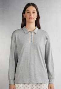 Grijs poloshirt met lange mouwen van zachte stof, voorzien van een kraag en een decoratieve knooplijst met kanten details in het midden.