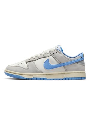 Niskie buty sportowe Nike w białej i jasno szarej skórze z niebieskim logo, niebieską podeszwą i niebieską wyściółką, widok z boku na białym tle.