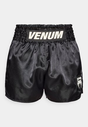 Pantalones cortos de boxeo de satén negro con cinturilla elástica que presenta un logo blanco "VENUM" y un parche de logo blanco en el lateral. Textura suave.