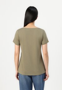 Ελαιοπράσινο κοντομάνικο μπλουζάκι με στρογγυλή λαιμόκοψη και χαλαρή εφαρμογή, φτιαγμένο από μαλακό ύφασμα, με ευθύ στρίφωμα και ελάχιστες ραφές λεπτομέρειες.