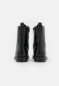 Černé kožené kotníkové boty s hladkou texturou, zadními zipy a malým podpätkem. Minimalistický design s nenápadnými švy.