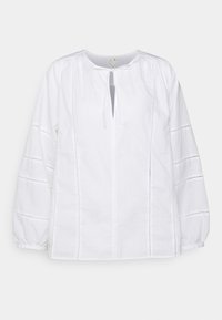 Blusa bianca in cotone con scollatura rotonda, nodo frontale e maniche lunghe. Presenta spalle arricciate e dettagli in cucitura orizzontale sulle maniche.