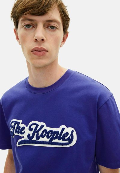 Lila Baumwoll-T-Shirt mit einem weißen und dunkelblauen gestickten Logo "The Kooples" auf der Brust, Rundhalsausschnitt und kurzen Ärmeln.