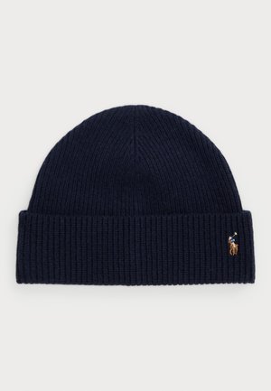 Navy blue ribbed knit beanie with small embroidered polo player logo on folded cuff against white background.