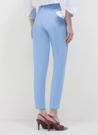 Hellblaue, figurbetonte Hose mit schlankem Design, knöchellang, zwei Gesäßtaschen, kombiniert mit roten, offenen High Heels mit Riemchen.