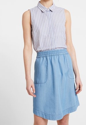 Haut sans manches à col avec des rayures verticales bleues et blanches ; associé à une jupe en denim avec une taille élastique et des poches latérales.