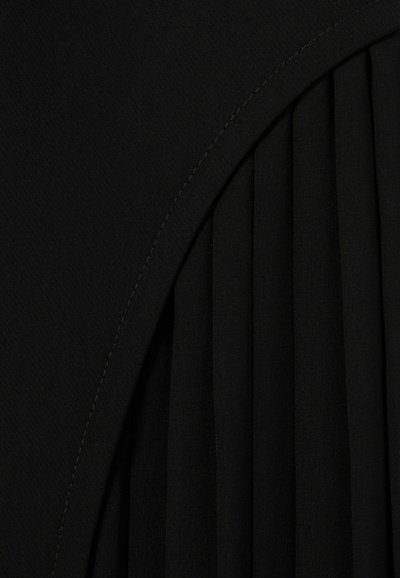 Tessuto nero con una superficie liscia, caratterizzato da pieghe sagomate e una cucitura curva. La cucitura è visibile lungo il bordo.