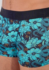 Colorful men's boxer trunk with a navy base, featuring large blue floral patterns and snake motifs, elastic waistband with logo.
