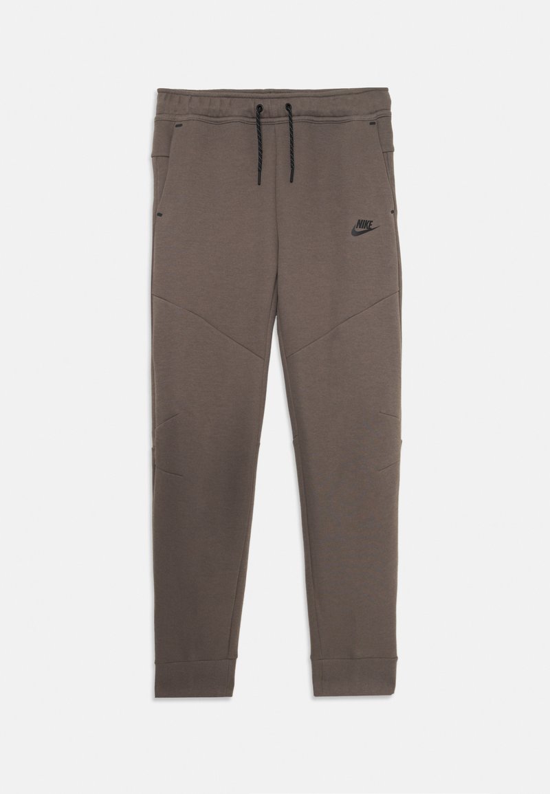 Nike treniņbikses, brūnas, izgatavotas no mīksta auduma, ar elastīgu jostu un auklu, sašaurinātiem galiem un nemanāmu logotipu pie kabatas.