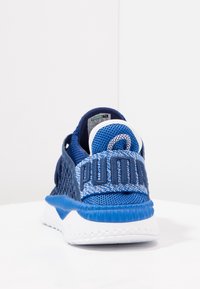 Buty sportowe Puma z niebieską siateczkową cholewką z teksturowanymi detalami, wyściełanym kołnierzem i białą środkową podeszwą. Wyraźne logo na boku.