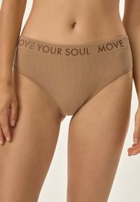 Beżowe majtki dla kobiet w prążki z szerokim pasem, na którym widnieje napis "MOVE YOUR SOUL" w ciemniejszym odcieniu. Gładka faktura.