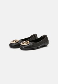 Ballerines en cuir noir avec texture matelassée, bout rond et logo doré proéminent à l'avant. Design classique avec un petit talon.