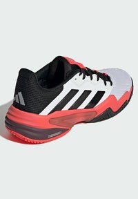 Schwarz-weißer Sneaker mit pinken Akzenten. Verfügt über ein Obermaterial aus Mesh, gepolsterte Sohle und drei schwarze Streifen an der Seite. Strukturiertes Außensohlenprofil.