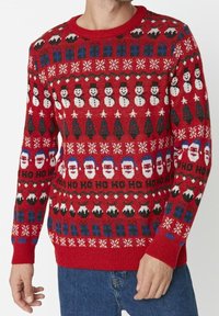 Red knitted sweater featuring holiday patterns: snowmen, Christmas trees, Santa faces, and snowflakes. Ribbed cuffs and neckline.