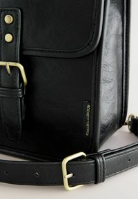 Czarna skórzana torebka na ramię o uporządkowanym kształcie, złote okucia, zapięcie na klamrę oraz metka z napisem "ROCKETT SEGEORGE".