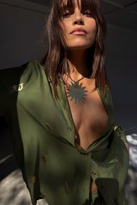 Roheline nööbitav särk lehemustritega, millel on sügav V-kaelus. Kantud päikesekujulise metallkaelakeega. Loomulik valgustus toob esile tekstuurid.