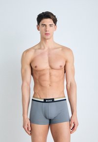 Gray boxer briefs made of soft fabric with a snug fit. Features a black and gold striped waistband with "BOSS" logo centered.
