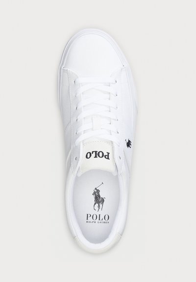 Vita kanvas sneakers med rund tå, platta snören och en svart logotyp. Har en vadderad krage och strukturera gummi sula.