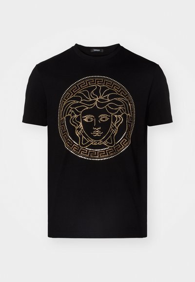 Juodas medvilninis marškinėliai su auksinėmis smeigėmis Medūzos dizainu ir graikų rakto ornamentu. Tiesus kirpimas su trumpomis rankovėmis.