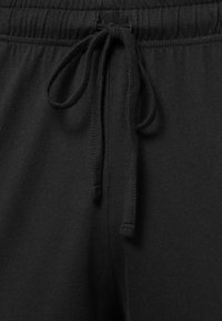 Schwarze Jogginghose mit Kordelzug, aus einem weichen, strukturierten Stoff gefertigt. Besitzt einen elastischen Bund und glatte Nähte.