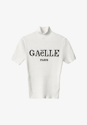 Maglione bianco a costine con collo alto e maniche corte. Presenta la scritta nera ricamata "GAËLLE PARIS" sul petto.
