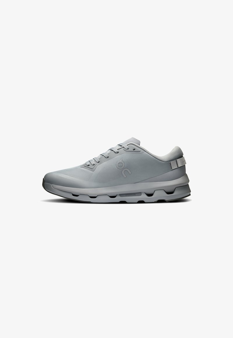 Grauer Sportschuh mit glattem Synthetikoberteil, Schnürsenkeln, gepolstertem Sohle und strukturierten Akzenten, mit einem Logo an der Seite.