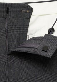 Sive karirane hlače s teksturiranim materijalom. Imaju crno dugme za zatvaranje, mali džep i kontrastnu bijelu podstavu.