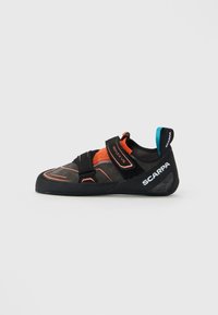 Svart og oransje SCARPA Reflex VS klatresko med to borrelåsremmer og en blå løftan på hælen, sett fra siden mot hvit bakgrunn.