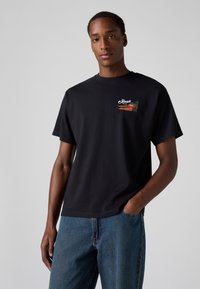 Black cotton t-shirt with short sleeves, featuring a colorful embroidered graphic of a carrot and the word "Fresh" on the left chest area.