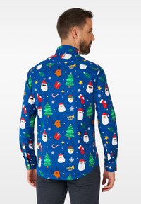 Camicia azzurra con bottoni caratterizzata da motivi a tema natalizio colorati: alberi di Natale, facce di Babbo Natale, renne, fiocchi di neve e regali.
