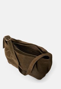Hnědá semišová taška přes rameno se širokým popruhem, vybavená zipovým uzávěrem a prostorným vnitřkem. Jemná textura a minimalistický design.