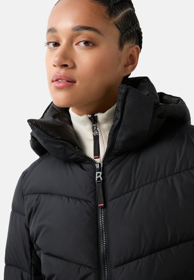 Schwarze Steppjacke mit hohem Kragen und Kapuze, mit diagonaler Naht, doppelten Reißverschlüssen und einer strukturierten Stoffoberfläche. Akzente umfassen ein Logo.