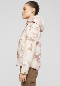 Lengva, su gaubtu striukė rožinės kamufliažo spalvos su smėlio spalvos detalėmis. Yra priekinės kišenės ir užtrauktukas. Lygus, atsparus vandeniui audinys.