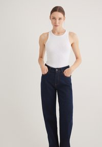 White ribbed tank top and dark blue denim wide-leg jeans. The jeans feature a high waist and classic 5-pocket design with contrast stitching.