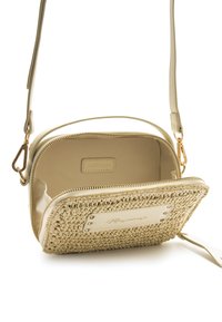 Bolso bandolera beige con un frente tejido, detalles de cuero, herrajes dorados y cierre con cremallera. El interior está forrado con una tela suave.