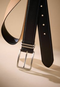 Ceinture en cuir noir avec une boucle en argent poli, texture lisse et plusieurs trous d'ajustement le long de la sangle.