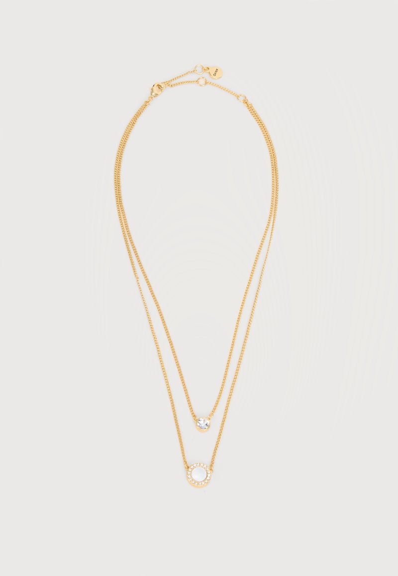 Κολιέ διπλής στρώσης χρυσής αλυσίδας με ένα μικρό κρεμαστό με διαφανές πολύτιμο λίθο στην κοντή αλυσίδα και ένα κυκλικό κρεμαστό με μικρές πέτρες στα κρύσταλλα στην μακρύτερη αλυσίδα.