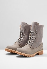 Stivaletti alla caviglia in suede grigio con design a lacci, colletto imbottito e suola in gomma. Presentano una punta liscia e pannelli laterali testurizzati.