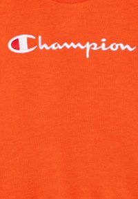 Sudadera de algodón naranja con logo "Champion" bordado en blanco. Textura suave con un diseño de cuello redondo.