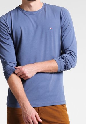 T-shirt blu a maniche lunghe in cotone morbido, con scollatura rotonda e un piccolo logo sul petto. Presenta polsini aderenti e una texture liscia.