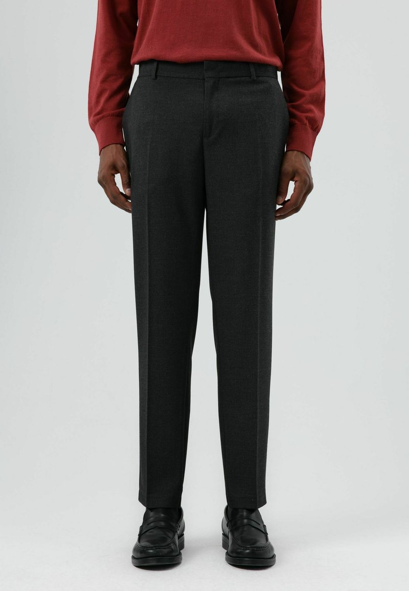 Donkergrijze, op maat gemaakte broek met een gladde textuur, smalle pasvorm, platte voorkant en riemlussen, gecombineerd met zwarte leren schoenen.