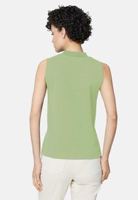 Mouwloze groene top met een hoge halslijn en een aansluitende pasvorm, gemaakt van zachte katoen. Gladde textuur, zonder zichtbare patronen of accenten.