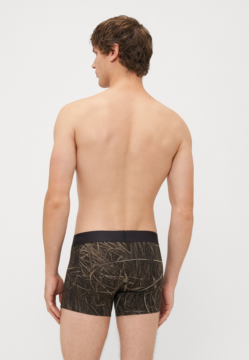 Szorty bokserskie w ciemnobrązowy i beżowy wzór w kamuflaż, z czarnym elastycznym pasem i dopasowanym krojem.